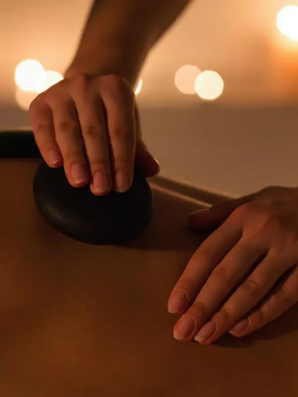 close up of hands massaging a back with hot stones