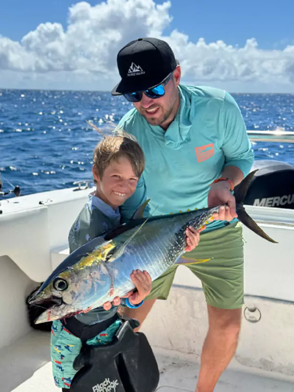 father and son posing with a large ocean fish that they've caught