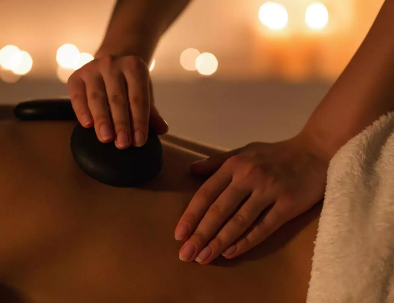 close up of hands massaging with hot stones